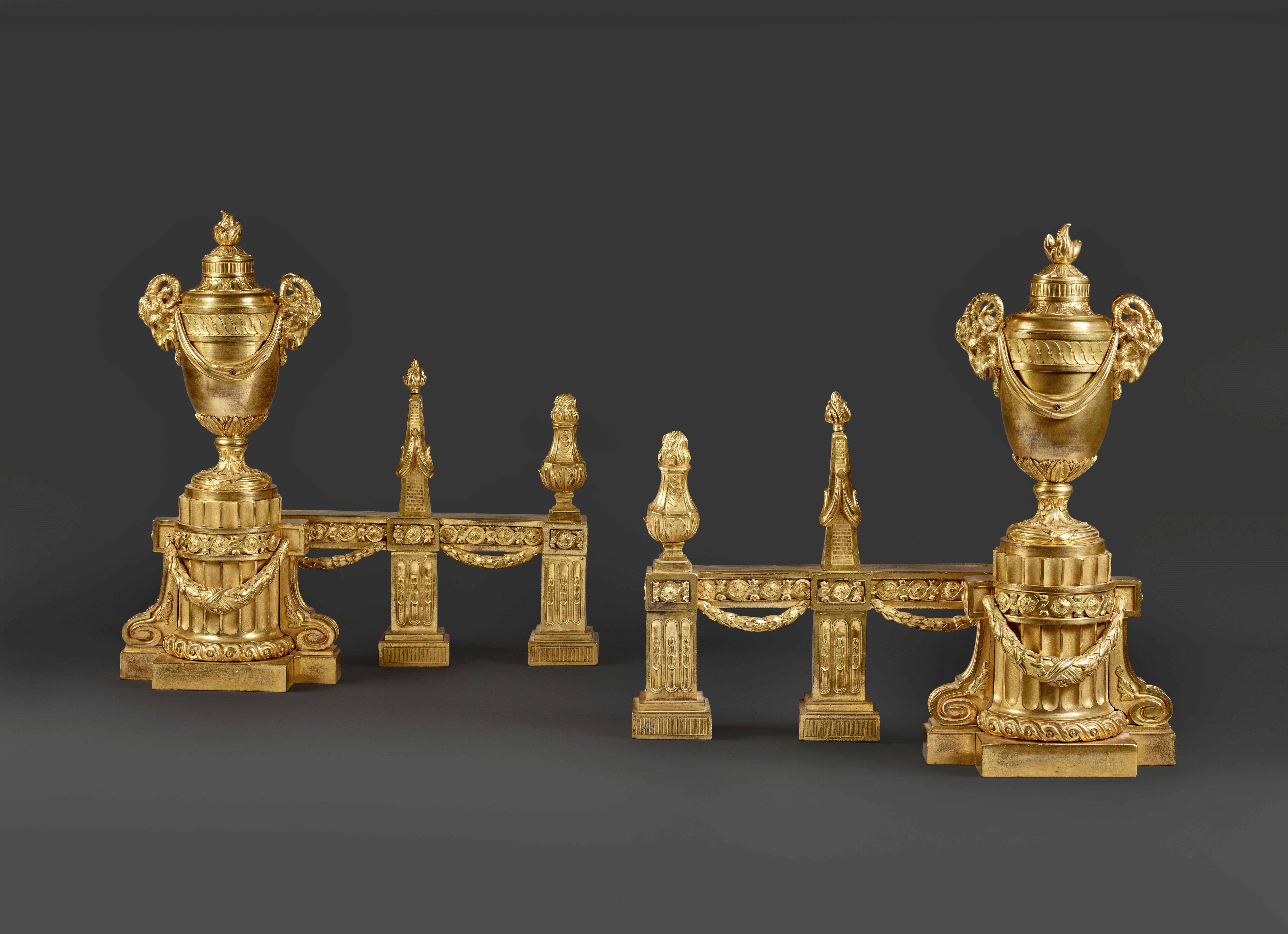 A pair of large firedogs with vase, pyramid and fire pot motifs in chased and gilt bronze
