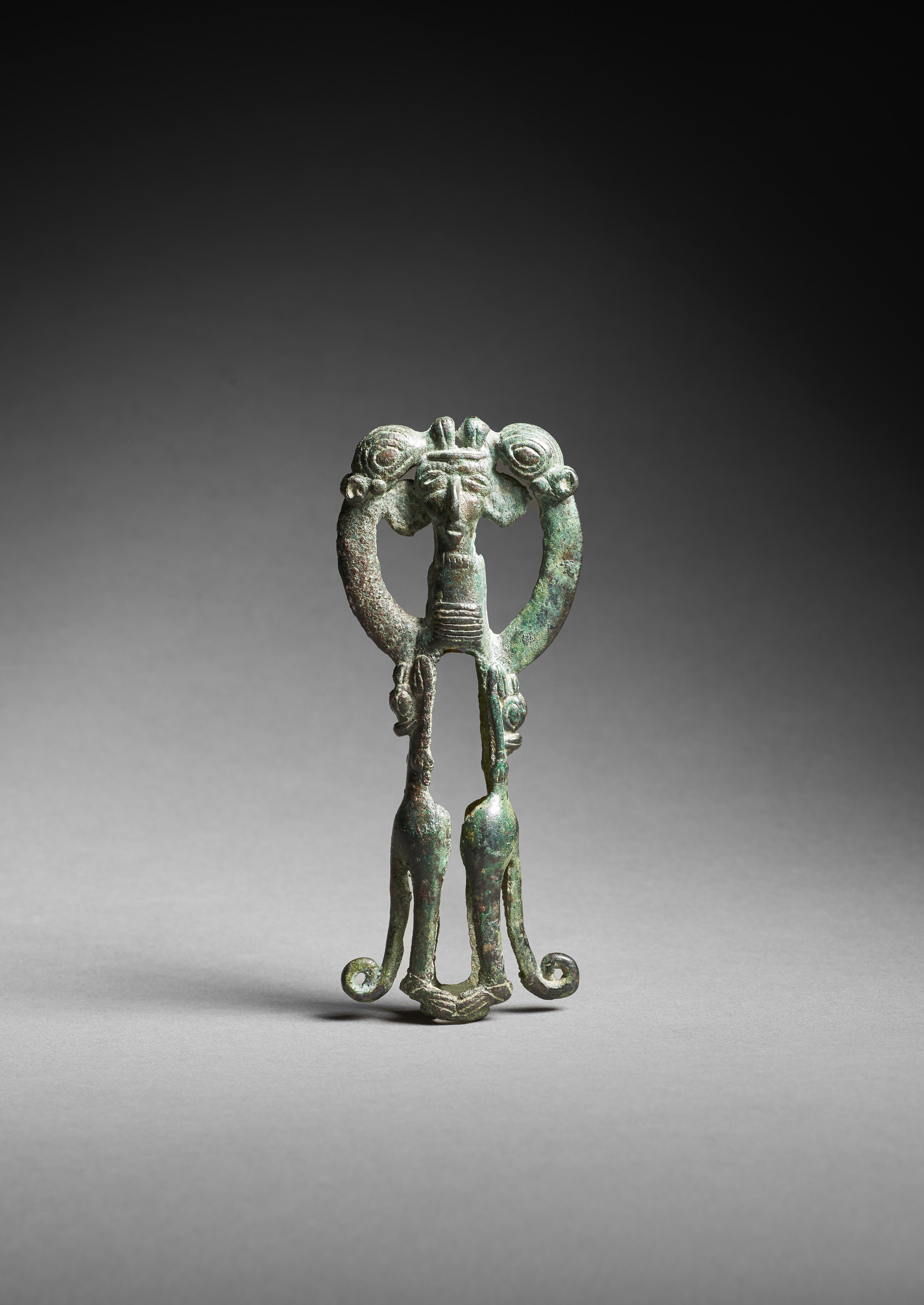 Finial with rampant lions holding a two-faced human mask.