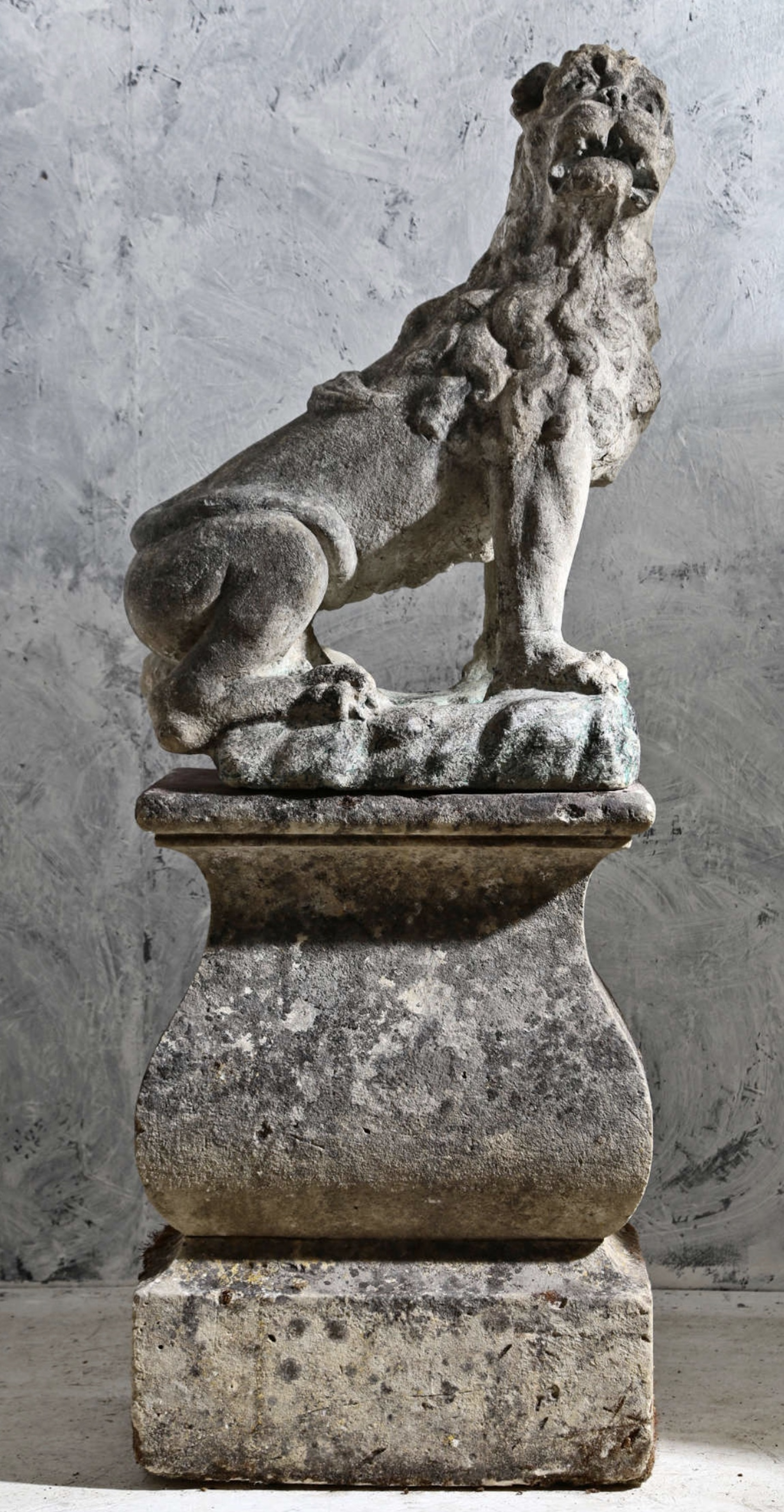 Lion d'honneur en pierre sculptée assis sur socle  balustre mouluré.