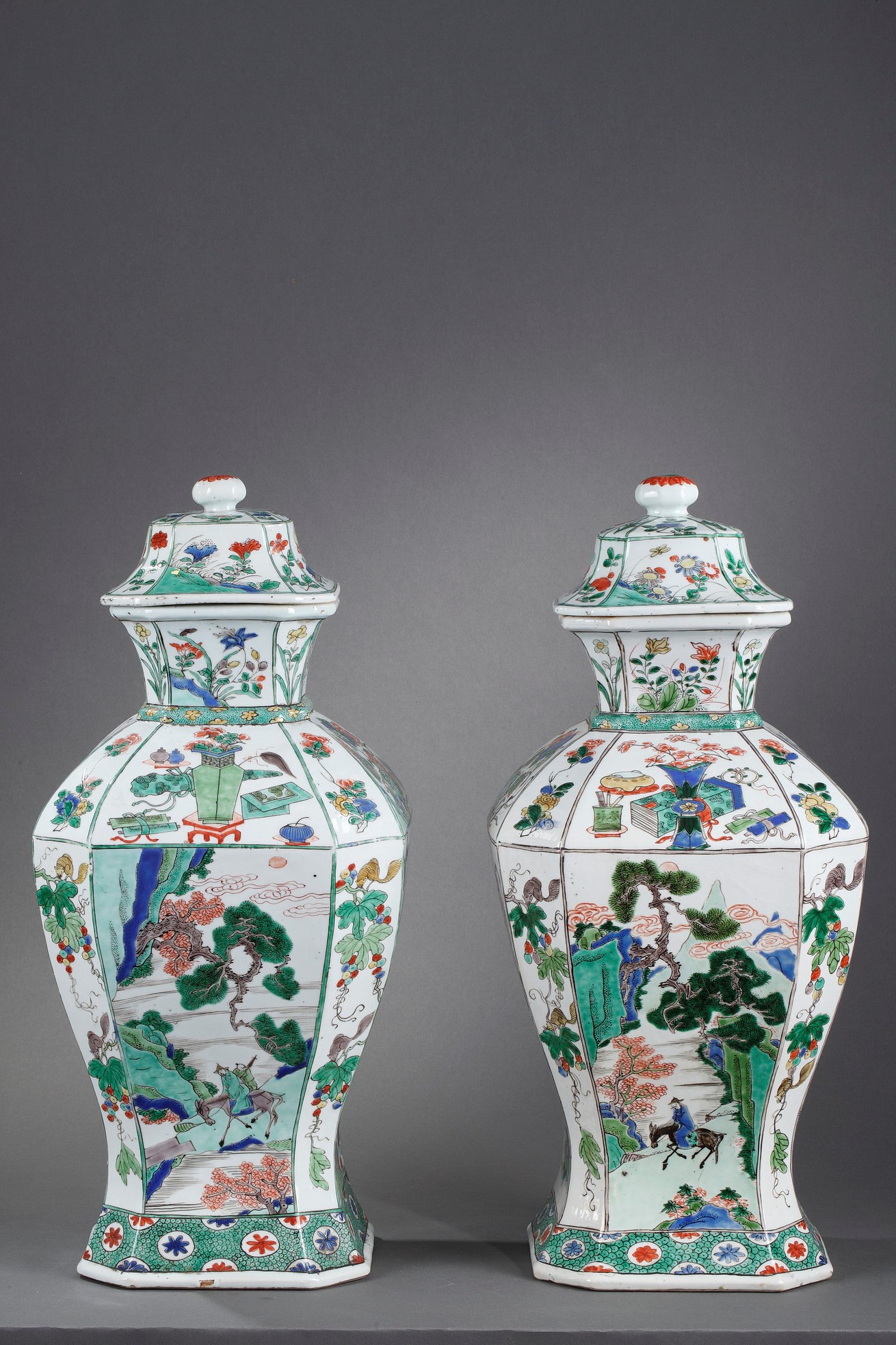 Paire de vases de forme quadrangulaire à pans coupés avec leurs couvercles en porcelaine de la "famille verte" au célèbre décor de personnage chevauchant une mule accompagné de son serviteur dans des paysages lacustres montagneux et d'oiseaux et lotus sur les grands côtés, les pans coupés ornés de loirs dans les raisins et l'épaulement de fleurs et rochers ou d'objets précieux.